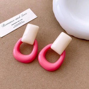 Detail of pink and cream geometric resin earrings on a textured brown background