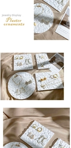 Detail view of white plaster jewelry tray with rock texture on satin fabric background