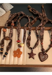 Detail of handmade linen fabric necklace straps with wooden beads and resin star pendants
