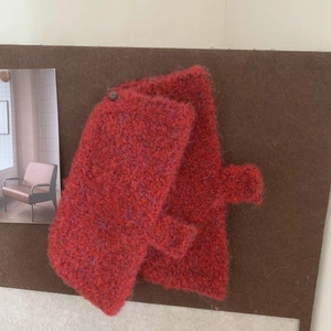 Cozy red knitted woolen gloves pinned on a corkboard as winter fashion accessory