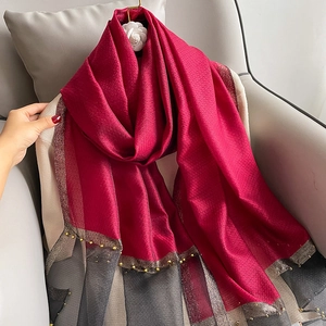 Detail of red and grey silk scarf with shimmering fabric and gold bead edge trim