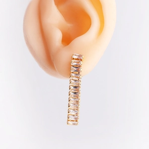 Detail view of long gold tassel earrings with rectangular zircon on silicone ear model