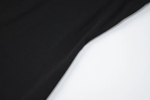 Close-up detail of high-quality stitching and black knitted fabric texture on the dress