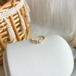 Detail of a gold butterfly ring with sparkling zircons on a white ceramic display
