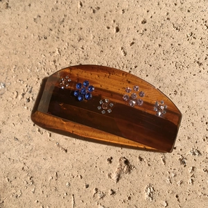 Detail of vintage amber hair clip with blue and pink rhinestone flower patterns