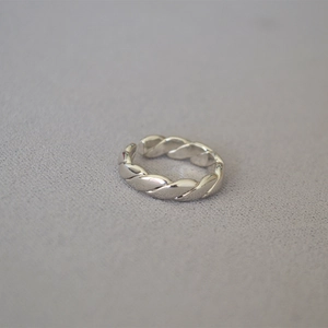 Makroaufnahme von silbernem gedrehtem Metallring mit polierter Oberfläche und offenem Band
