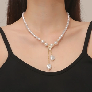 Baroque pearl necklace with white flower detail and hanging tassels on a model