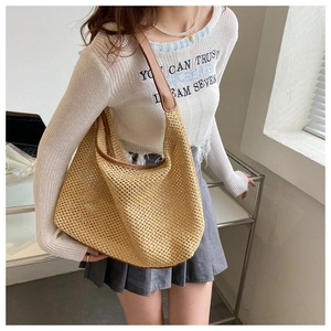Detail of hollow woven straw shoulder bag with brown leather strap for summer beach vacation