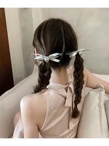 Detail view of silver satin bow hair ties with heart pendants on braided hairstyles