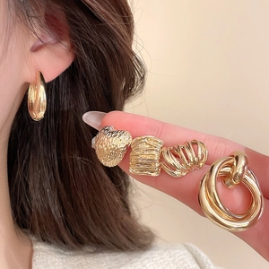 Detailed macro view of gold-toned textured heart studs and minimalist hoop earring set