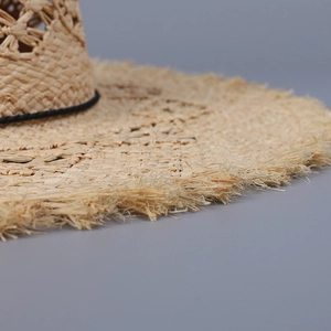 Macro detail of hand-woven raffia sun hat with star hollow patterns and fringe edges