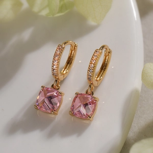 Macro di orecchini a cerchio dorati con ciondolo in zircone rosa quadrato su ceramica