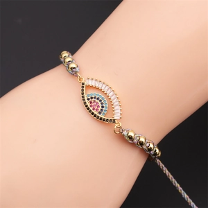 Macro shot of boho braided evil eye bracelet with colorful zircons and golden beads