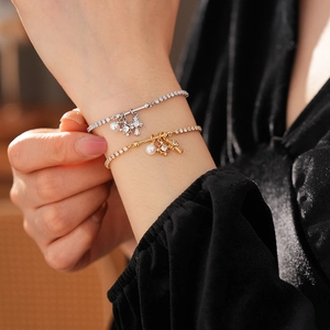 Detailed close-up of layered zircon cross bracelet with pearls on a female wrist