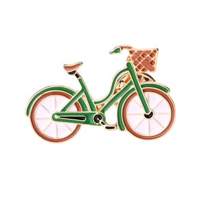 Detail of green and gold bicycle brooch with enamel finish and white wheel accents