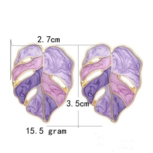 Detailed view of purple gradient Monstera leaf earrings with golden enamel edges