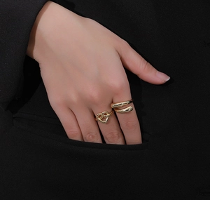 Close-up of heart knot and double-layer gold rings worn by model on black background