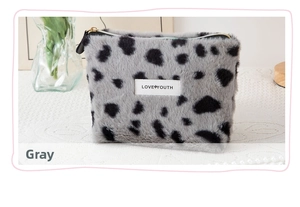Close-up of grey leopard print faux fur makeup bag with gold zipper on white tablecloth