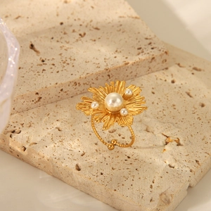 Macro shot of gold floral pearl ring with irregular petals on a stone surface