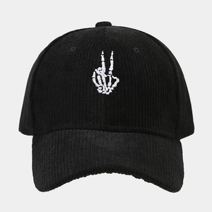 Detailed close-up of white skeleton hand embroidery on black corduroy baseball cap