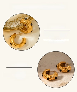 Macro detail of croissant-style gold earrings with black stone inlays and polished finish
