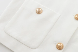 Close-up of white textured fabric with elegant gold embossed round metal buttons