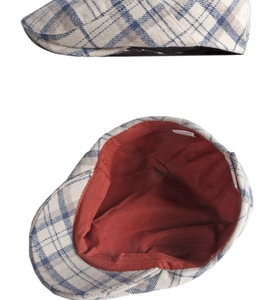 Detail of classic plaid newsboy cap showing grey wool pattern and red inner lining fabric