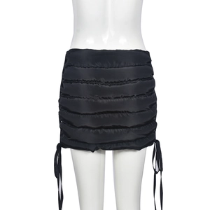 Detail of black quilted mini skirt featuring side drawstring ties on a white mannequin