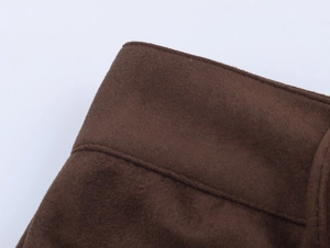 Macro detail of brown faux suede fabric showing precision stitching on garment hem