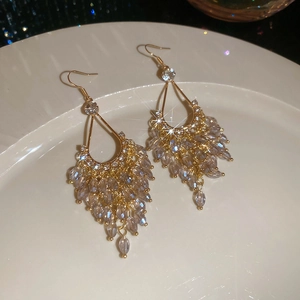 Detail of drop-shaped gold earrings with lavender crystal fringe on a ceramic plate