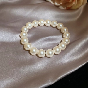 Vue détaillée d'un bracelet en perles plaqué or 18 carats sur un élégant tissu en soie champagne