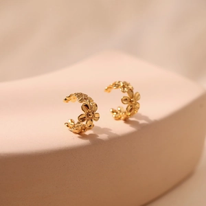 Macro shot of 18K gold plated brass ear cuffs with a delicate small daisy flower design