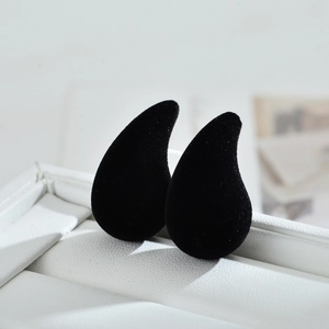 Macro shot of black velvet teardrop earrings in a white gift box with soft texture