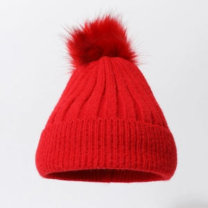 Solid red knit beanie with faux fur pompom and elastic ribbed texture for winter warmth