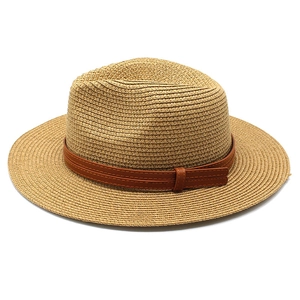 Détail du tissage en paille naturelle et bande en cuir marron avec coutures sur le chapeau