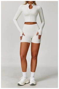 Detailed shot of white long-sleeve zipper top with thumb holes and high-waisted gym shorts