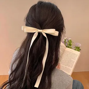 Elegant cream bow hair clip with long ribbons worn on the back of a woman's head
