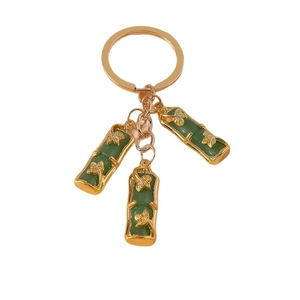 Bamboo style gold keychain with green faux jade pendants and lucky pig charm on white background