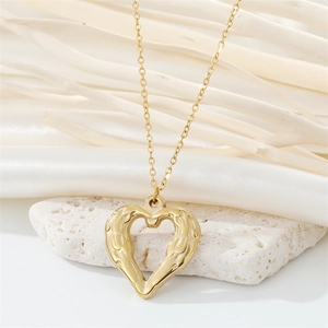 Macro shot of gold heart pendant with textured feather surface on a white stone background