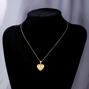 Detail showing a gold heart pendant with letter A engraving on a black mannequin
