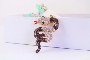 Macro view of crystal snake pendant with gold plating and red enamel details