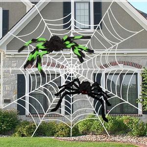 Outdoor Halloween decor showing giant plush spiders on a large white web against a house