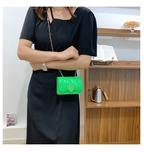 Detail of girl wearing bright green heart-shaped silicone bag with golden chain