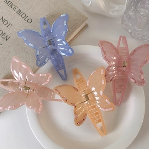 Detail of four colorful butterfly hair claws with delicate stitched edges on a white tray