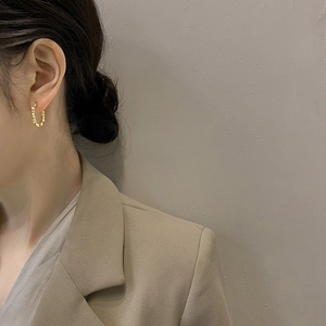 Detailed view of champagne gold hoop earrings with beaded texture on model ear