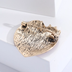 Detail view of the gold heart brooch back showing the vintage texture and secure safety pin