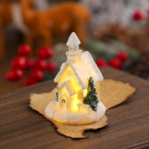 Close-up of white resin Christmas village house with warm LED glow on vintage paper