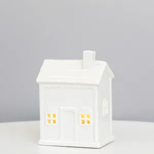 Detailed view of white ceramic house with cross-cut windows and warm LED glow, 12.5cm height