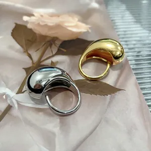 Polished gold and silver drop rings with a minimalist teardrop shape and glossy metal finish