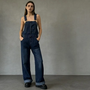 Detailed view of adjustable shoulder straps and chest pockets on navy denim dungarees